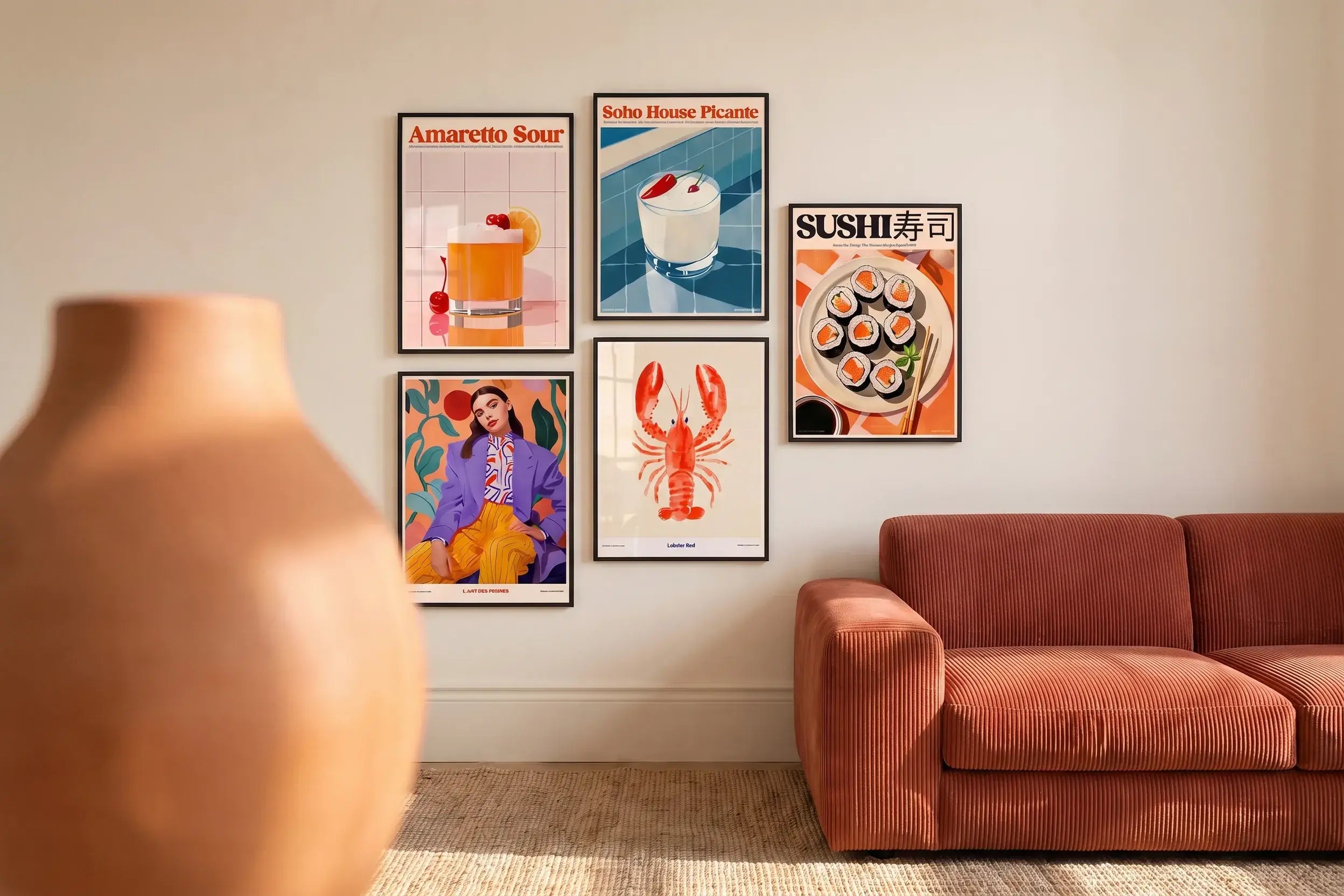 Moderne Poster-Galerie an weißer Wand mit gerahmten Kunstdrucken – Amaretto Sour Cocktail-Poster, Soho House Picante, Sushi-Print, Lobster Red Illustration und L'Art des Femmes – neben einem terrakottafarbenen Samtsessel